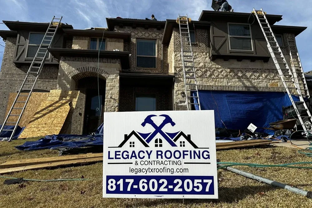 Two-story home mid-job with ladders up and a Legacy Roofing yard sign out front